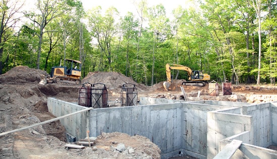 Excavators clearing dirt near a foundation