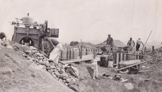 Workers pouring concrete foundation by hand